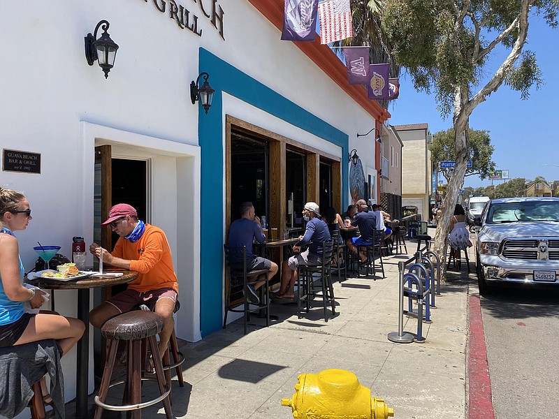 Customers dining on the sidewalk in front of Guava Beach Bar and Grill in Mis...