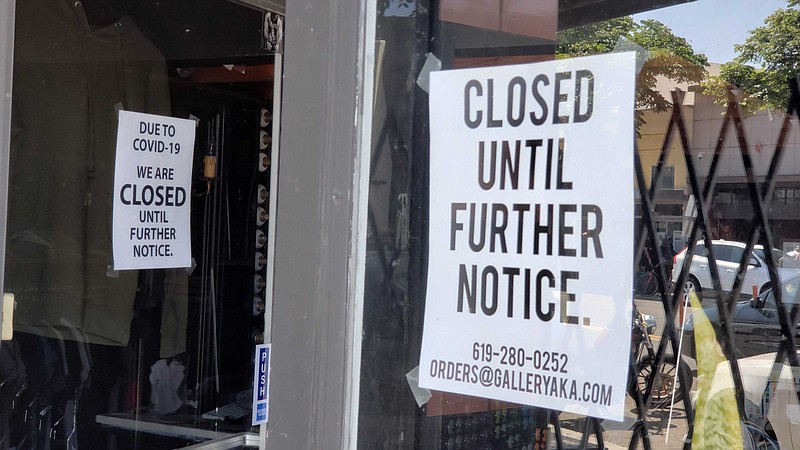 A sign hanging on the window of AKA Gallery in North Park explaining it is cl...